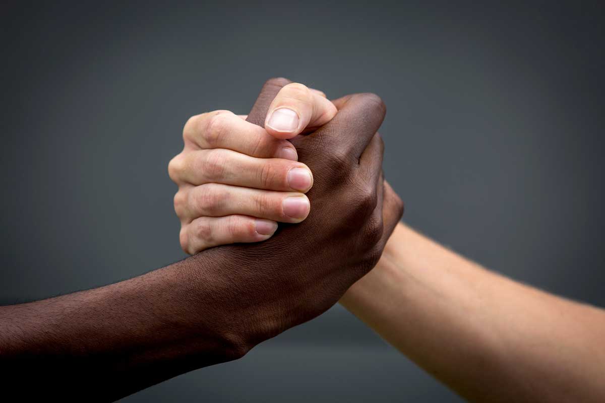 black and white hands clasp together