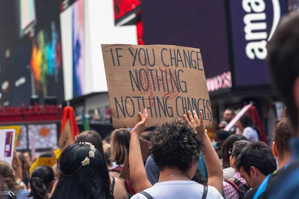 Protester with sign that says: "If You Change Nothing, Nothing Changes."