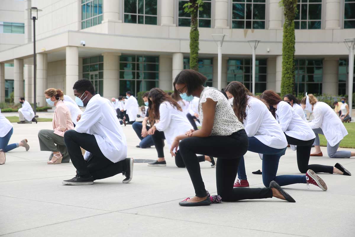 Group of people kneel in College of Medicine courtyard