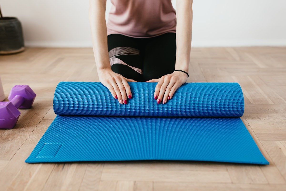 woman rolls up yoga mat
