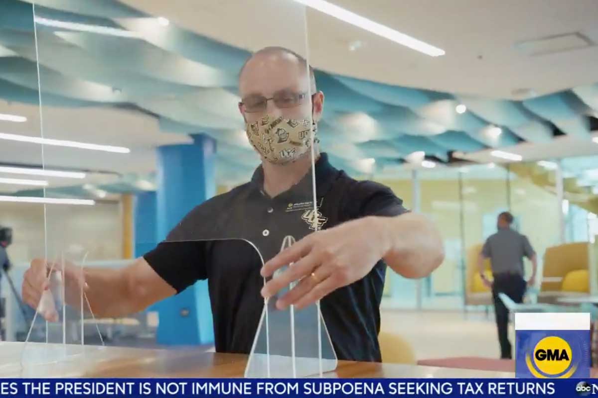 man wearing face mask installs Plexiglass on counter