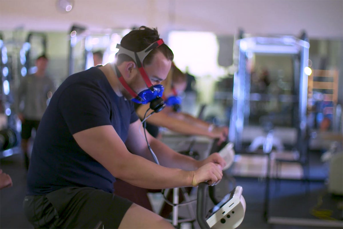 man rides exercise bike while wearing a face mask