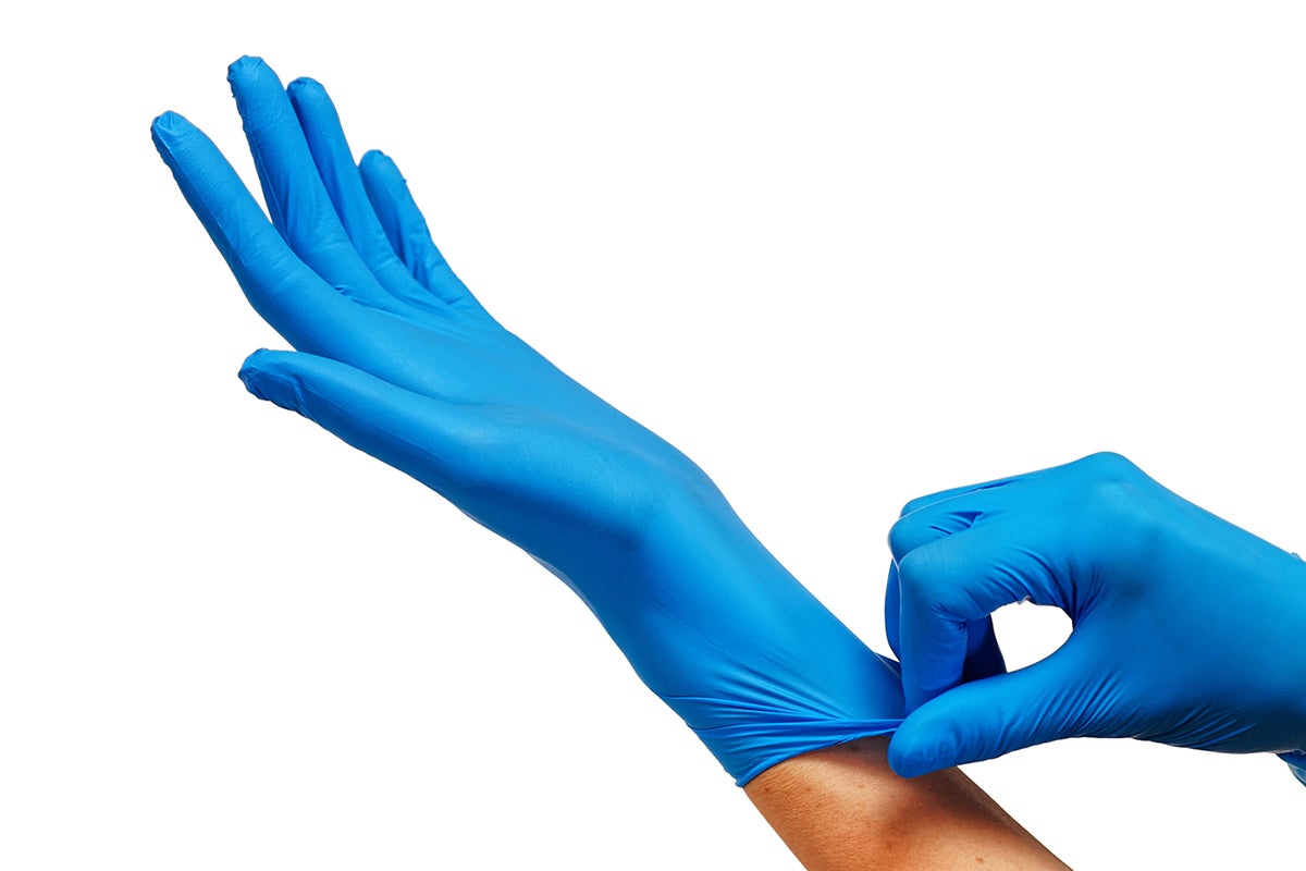 Doctor putting on protective blue gloves isolated on white background