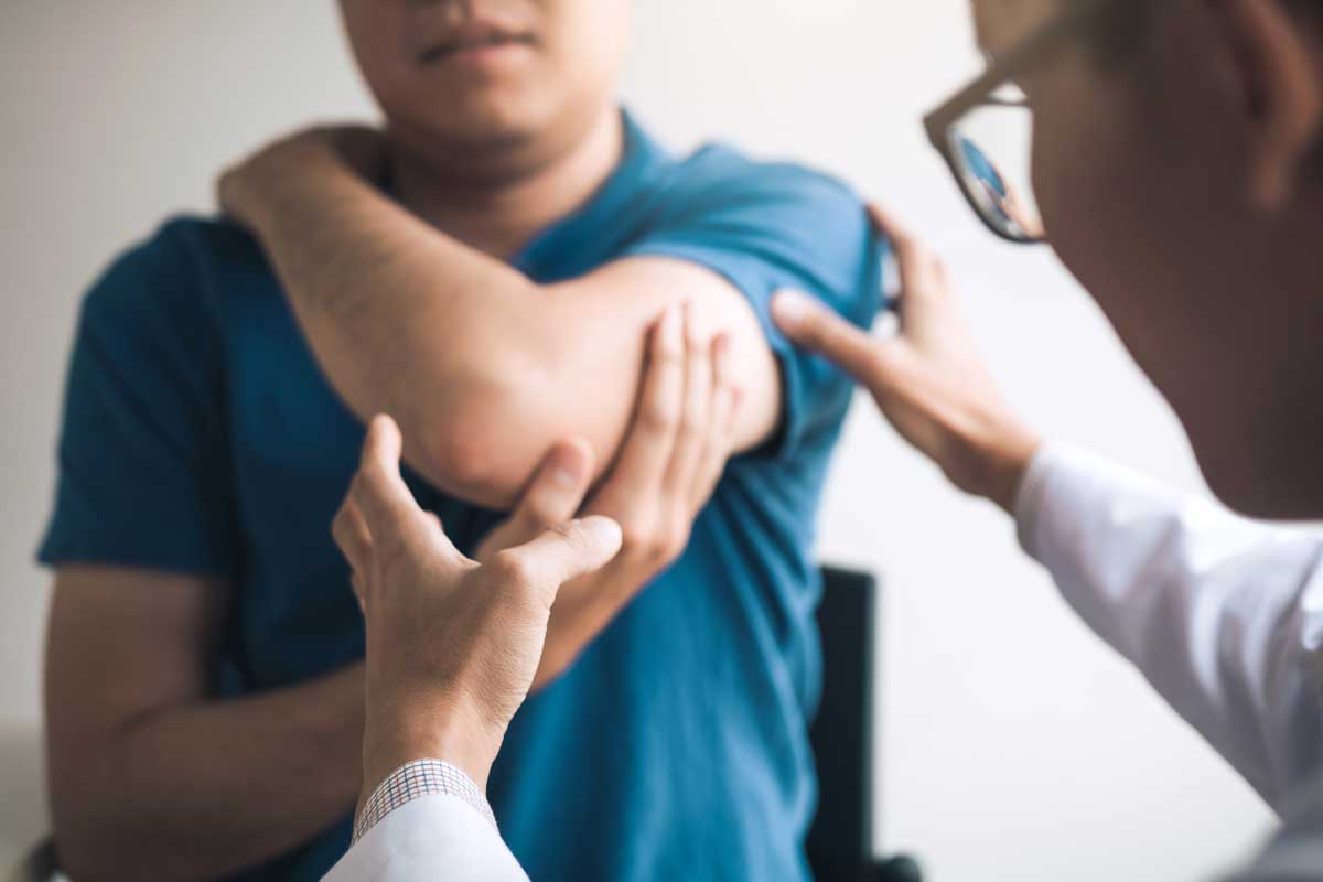 therapist examines a man's elbow