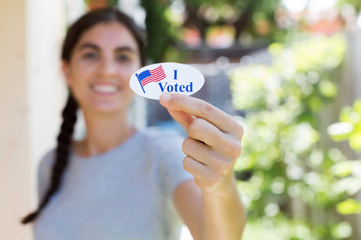 Woman holds an "I voted" sticker