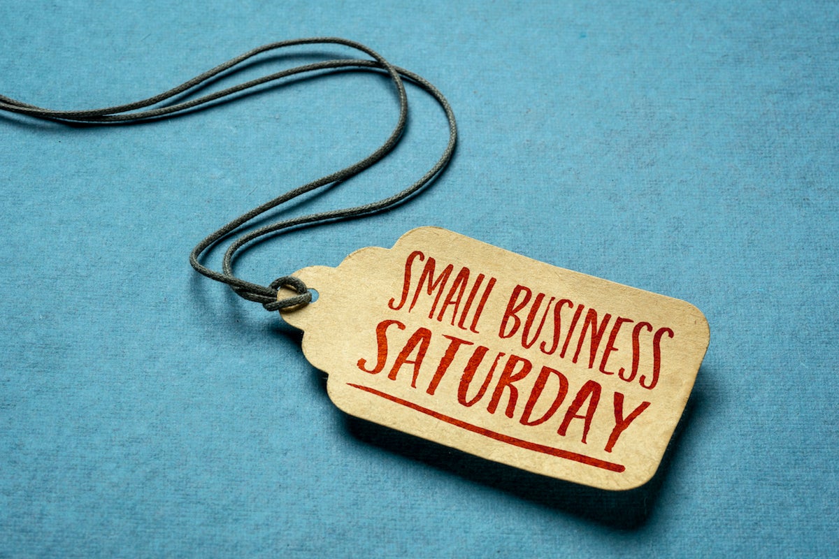 Small Business Saturday sign - a paper price tag with a twine against blue paper background, local holiday shopping concept (Small Business Saturday sign - a paper price tag with a twine against blue paper background, local holiday shopping concept, A