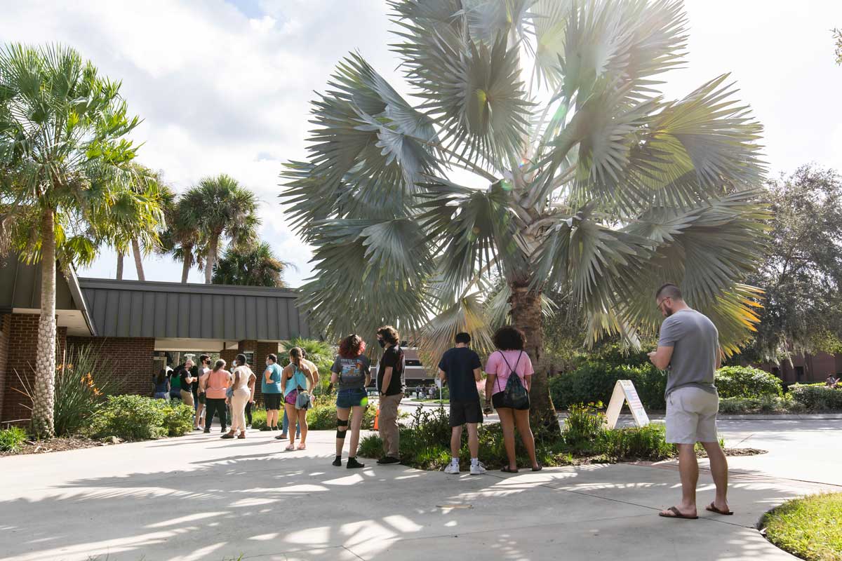 students wait in line to vote at Live Oak Event Center on sunny day