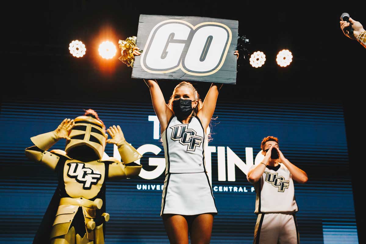 UCF cheerleaders and Knightro pump up crowd with sign reading "go"