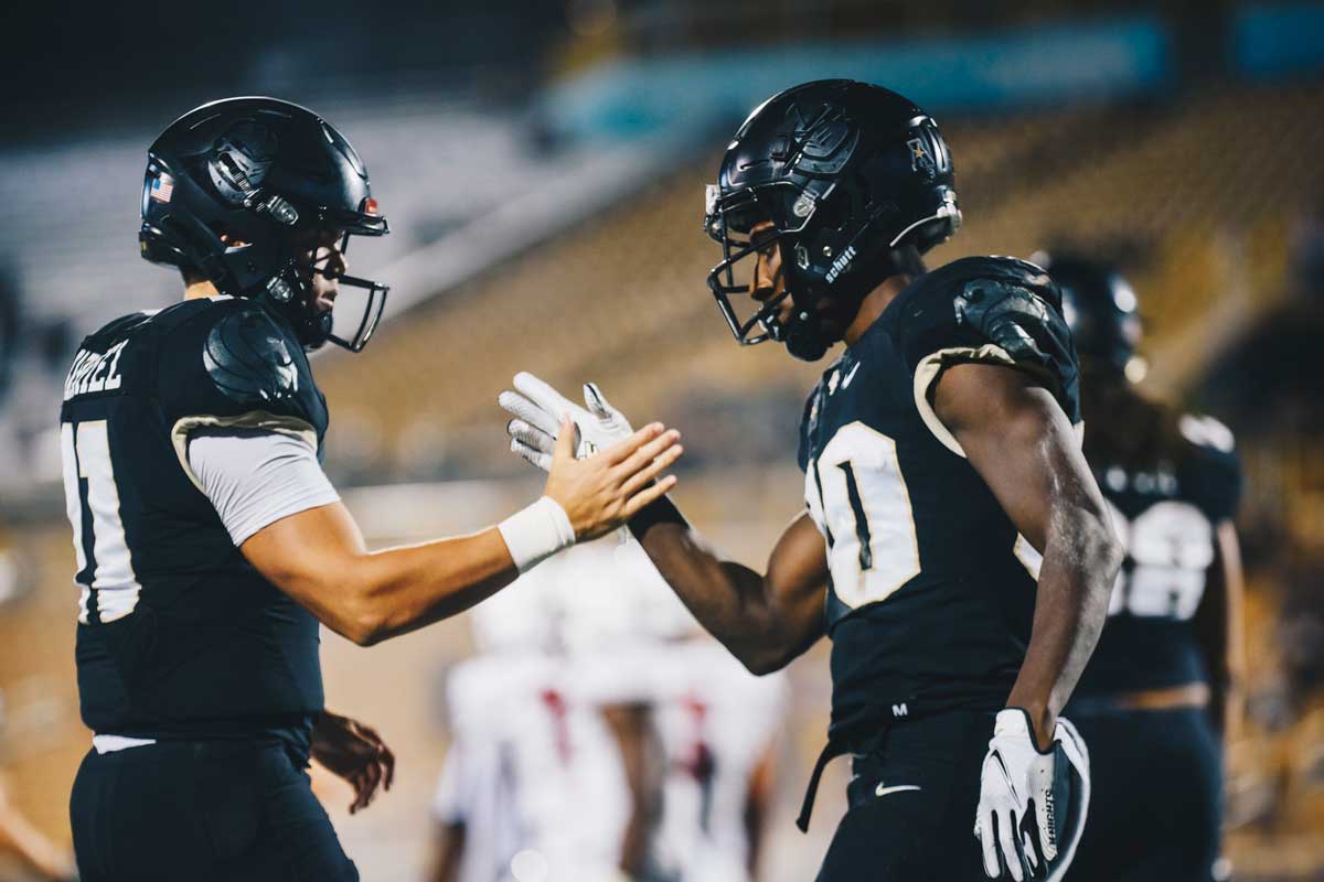 Dillon Gabriel and Greg McCrae handshake while in uniform