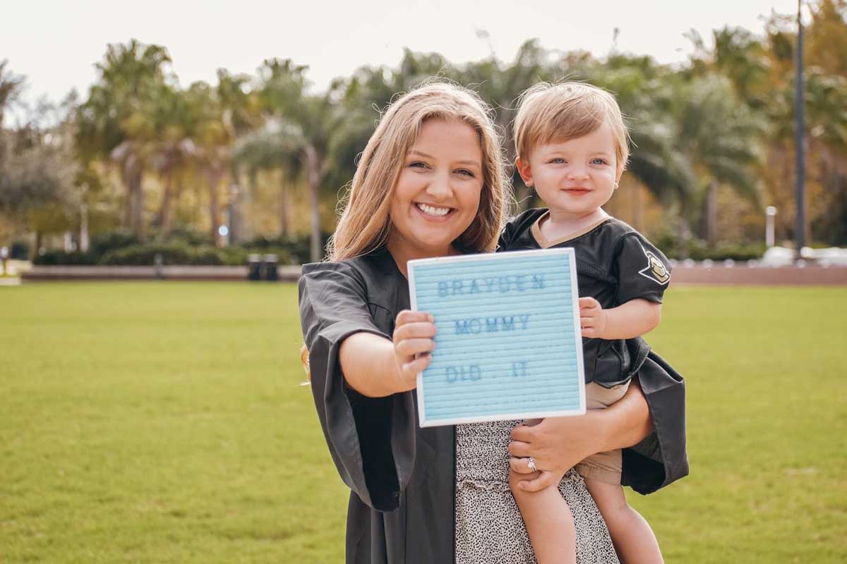 Lindsey Palm holds her son and a sign that reads "Brayden's mommy did it"