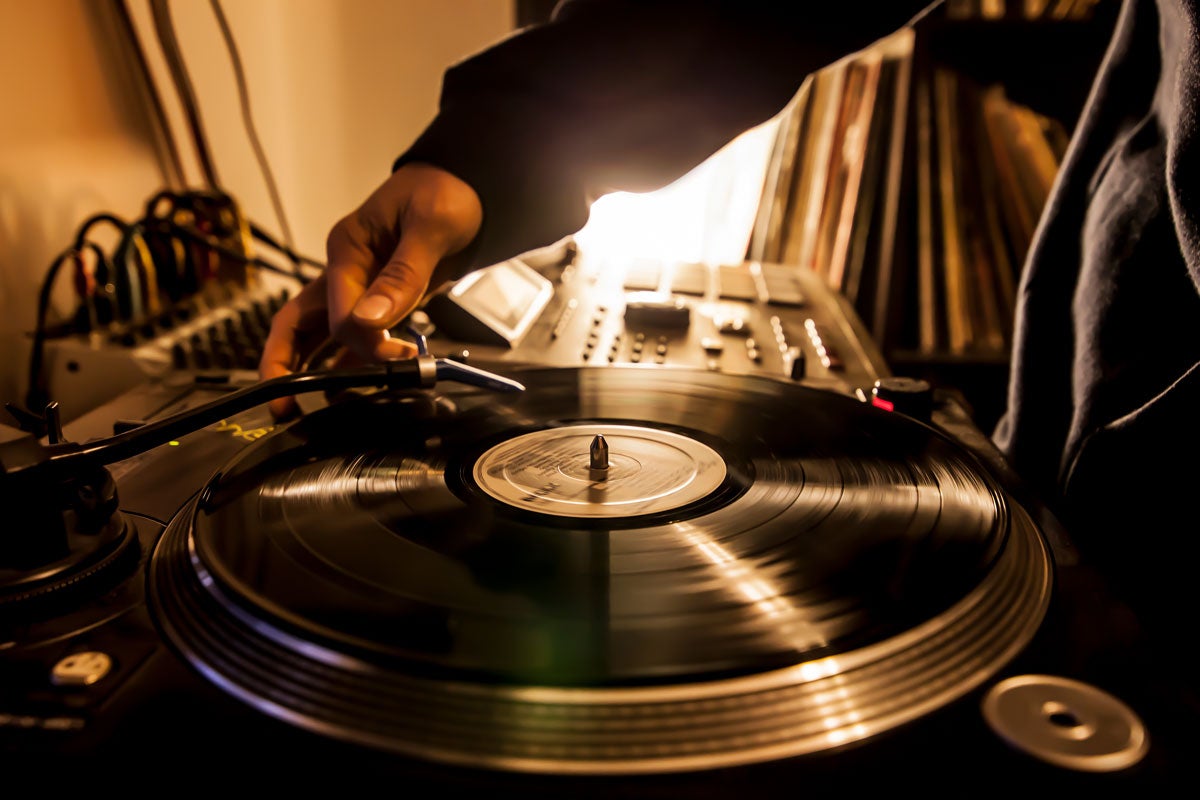 black hand lifts needle on vinyl record player