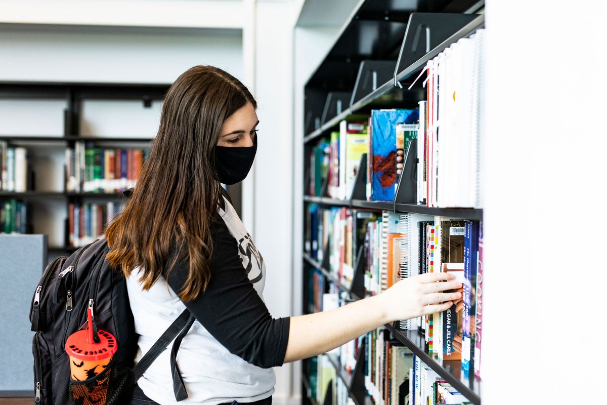 woman student browses books on shelves