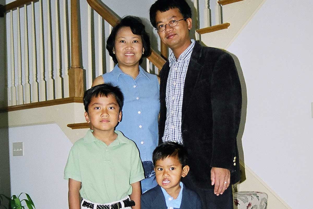 Mother and Father stand behind their two sons near a staircase