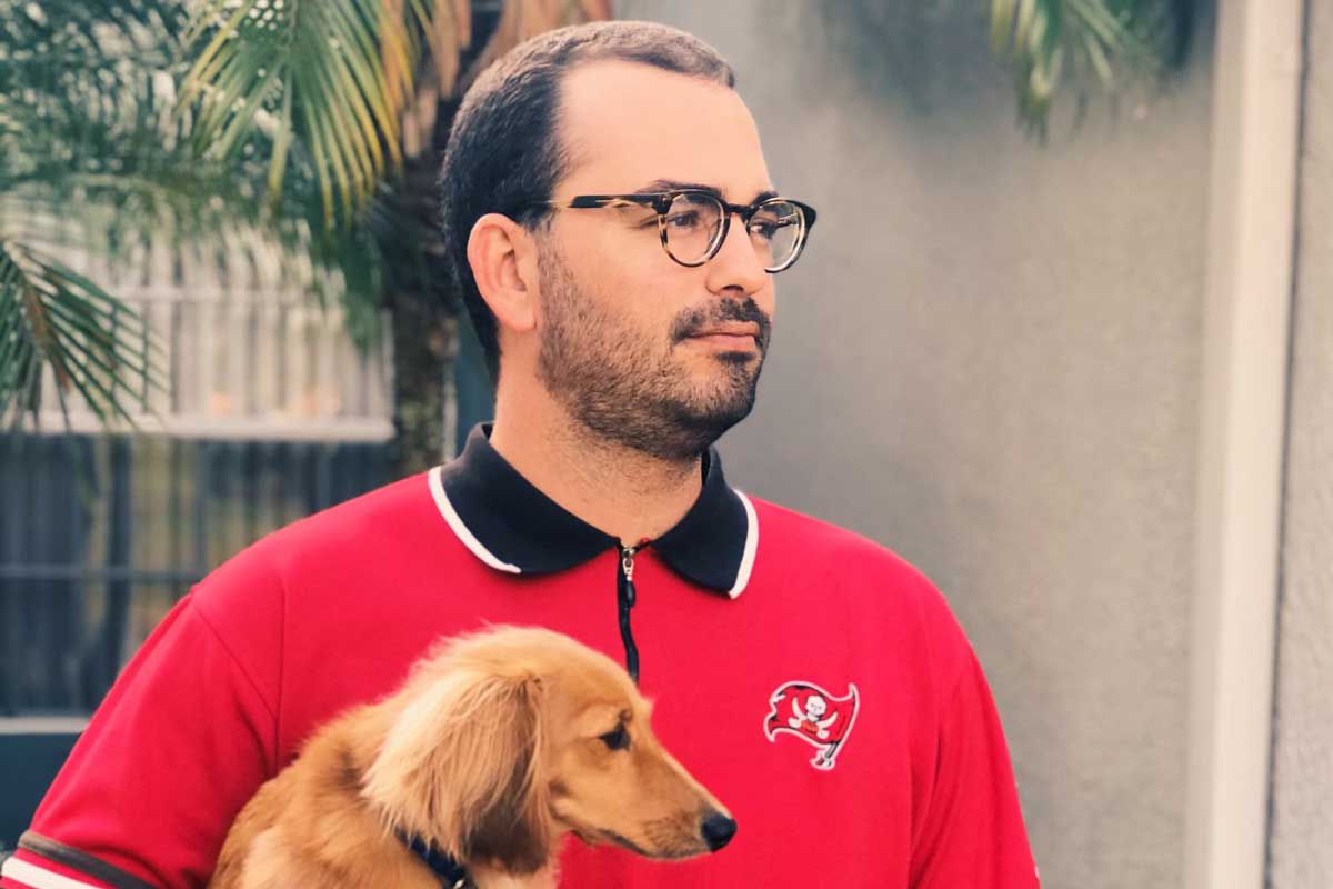 Joey Nelson in red Bucs polo while holding his dog, Ace