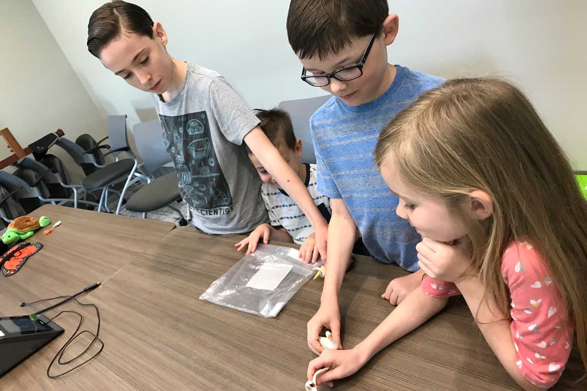 four children huddle around a table with animation equipment