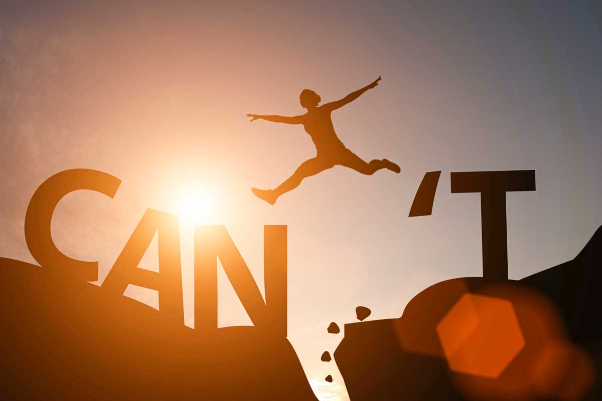 Silhouette of a person soaring from one boulder to the next, jumping over the word Can't