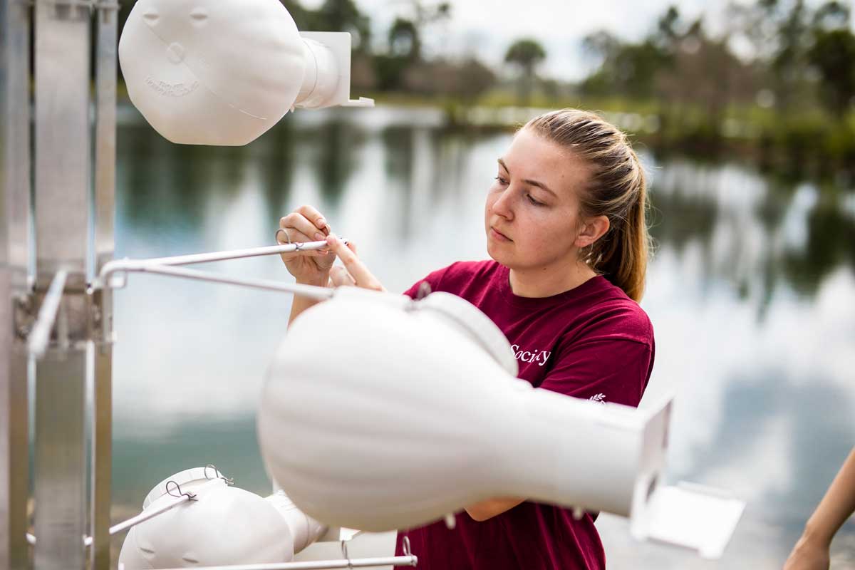 Blonde student in a red shirt works on a white birdhouse