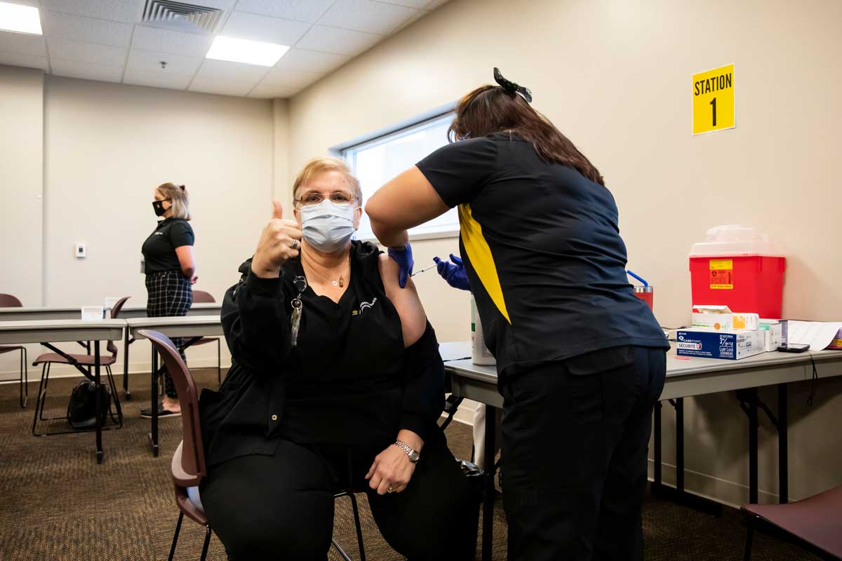 Woman gives a thumbs up of approval as she receives her COVID-19 vaccine