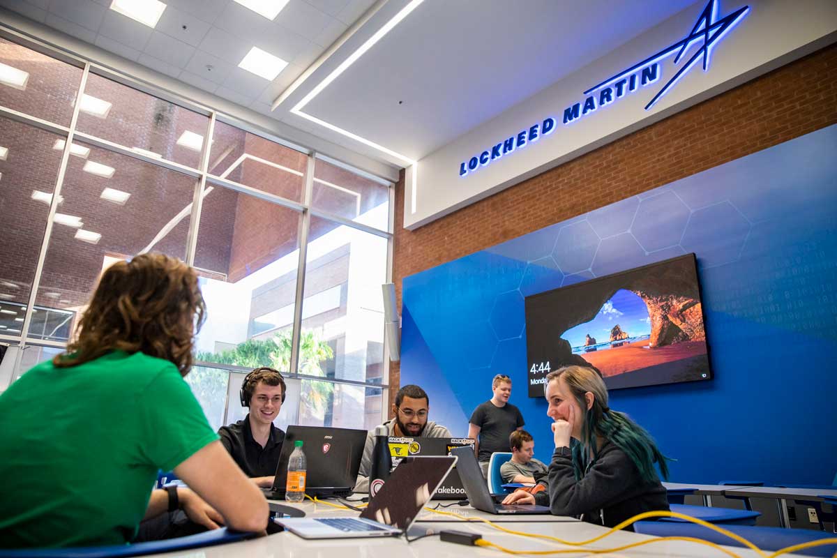 Four students sit at a desk with computers at Lockheed Martin Cyber Innovation Lab