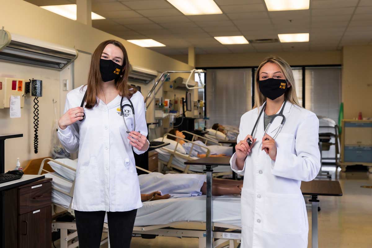 Two women nurses wearing black face masks in a hospital room