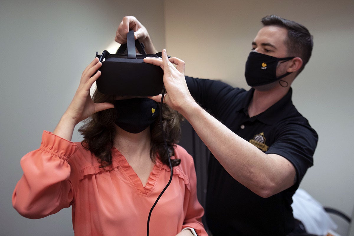 man helps fit a woman with a VR headset