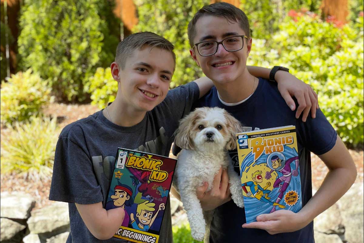 Zachary and Christo Pamboukas hold issue 1 and 2 of The Bionic Kid along with their dog