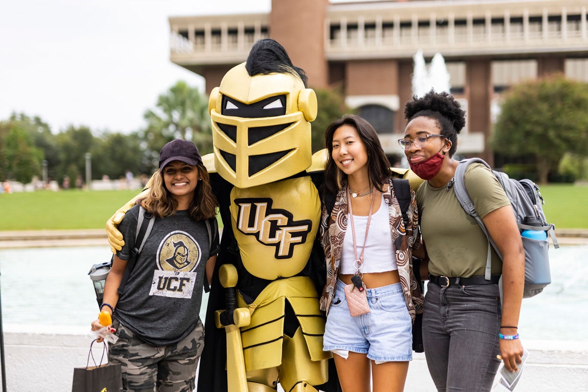 Knightro poses for a photo with three women students