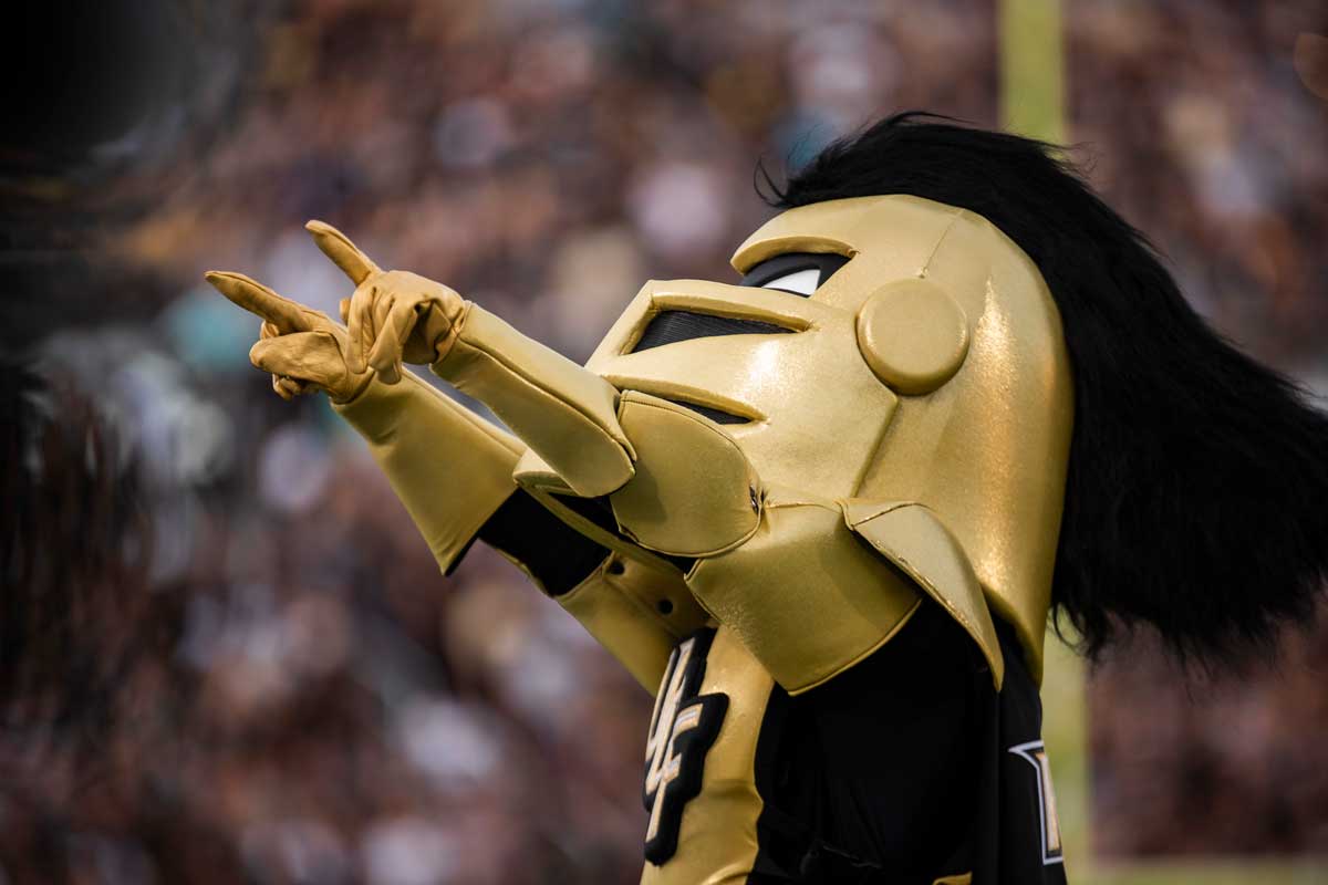 Knightro points with both hands to the crowd