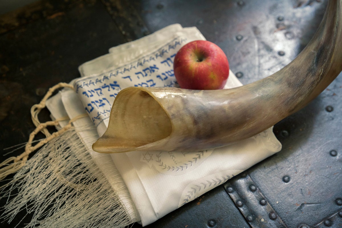 Close up of shofar ,Hebrew prayer book and apple on a table