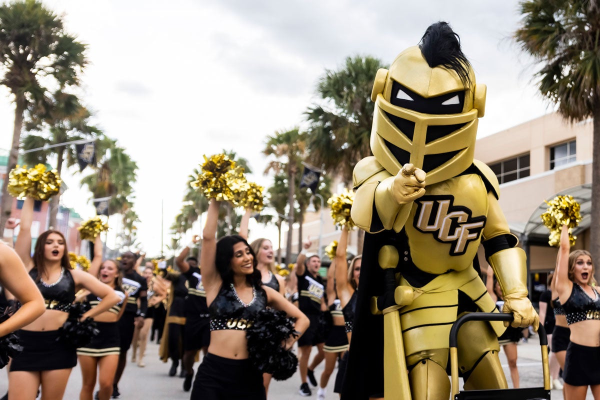 Knightro points while on the March to Victory with cheer team