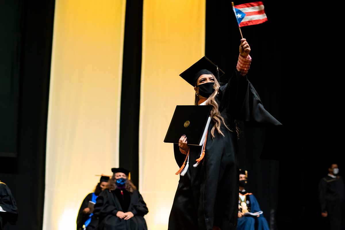 UCF grad waves a Cuban flag as she crosses the stage at commencement