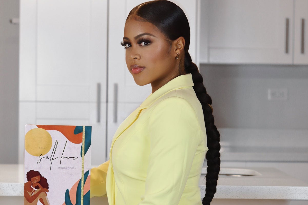 Black woman wearing a yellow business suit holds a book