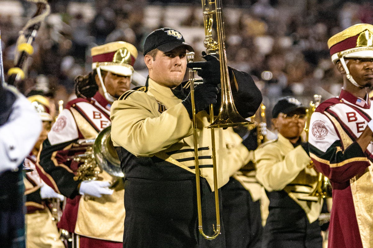 UCF band member stands next to B-CU band member in formation