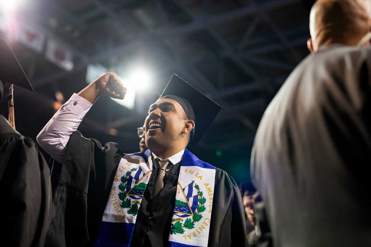Male graduate in black cap and gown pumps fist in the air
