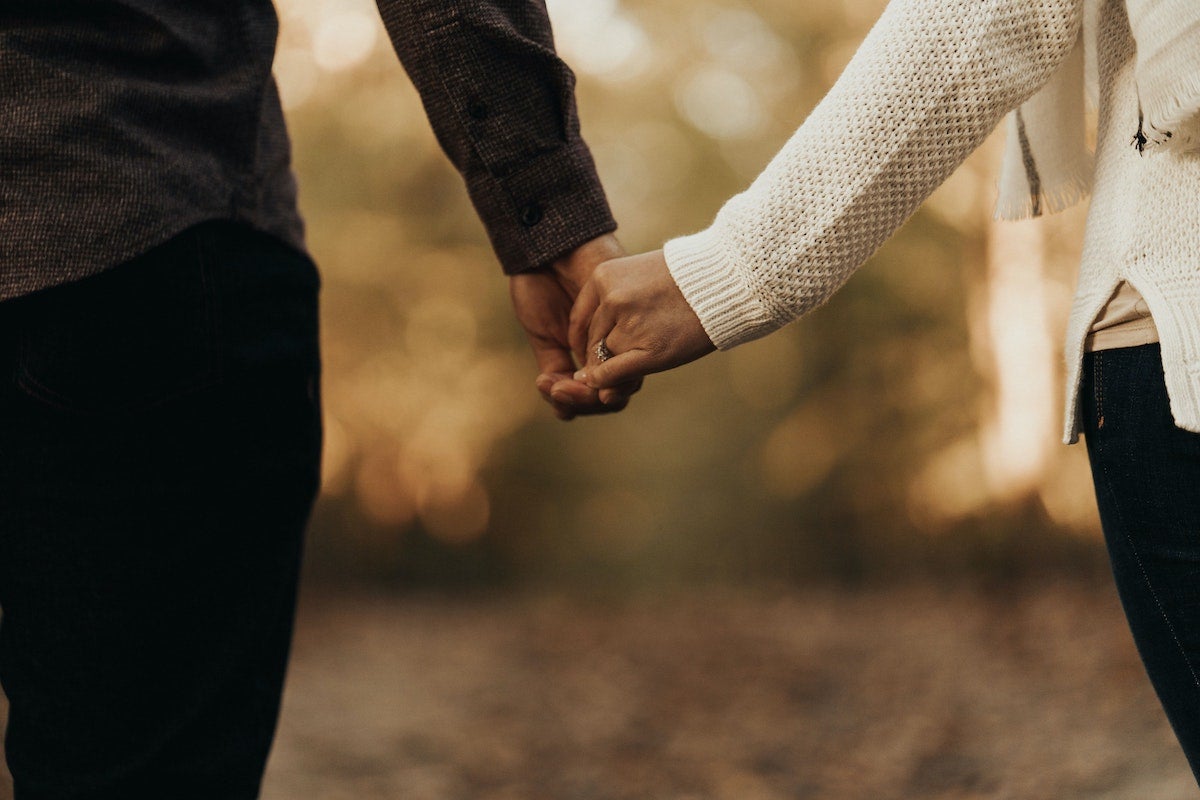 cropped photo from the waist down of an engaged couple standing and holding hands