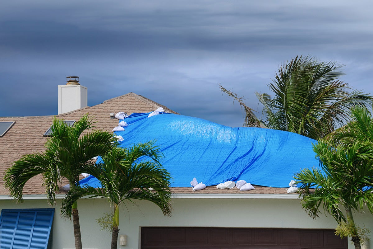 a tarp is secured to the roof of a house during a storm