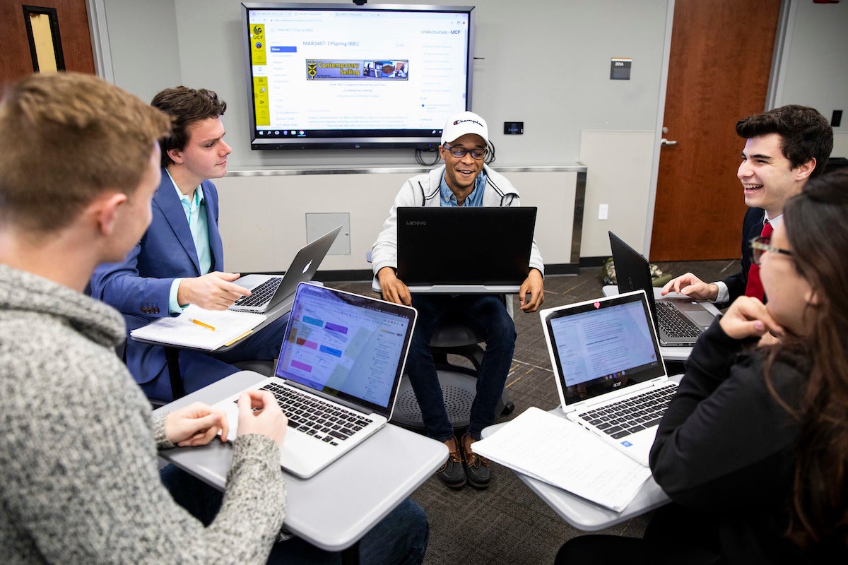 Students working in a group on their laptops in class