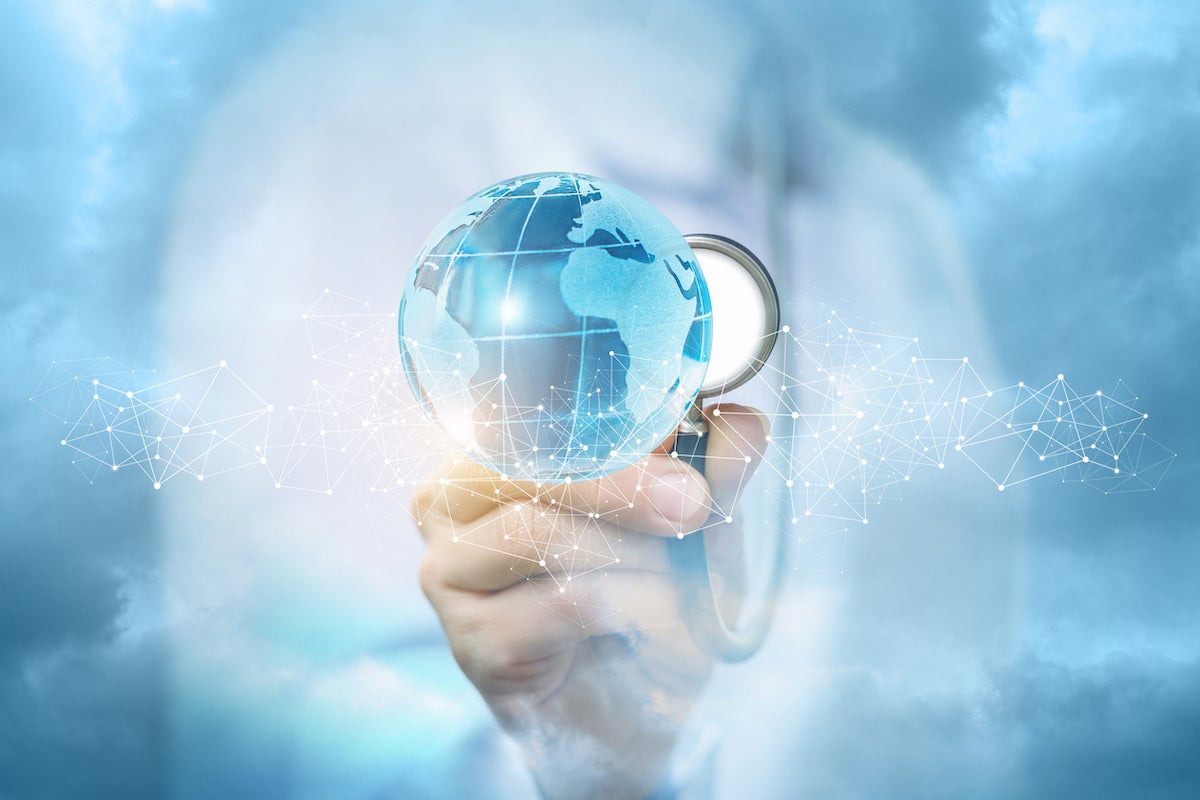 A doctor in the medical uniform is carefully touching a bright global map with a stethoscope behind a slight chain of tiny wireless connections . The concept of global health care.