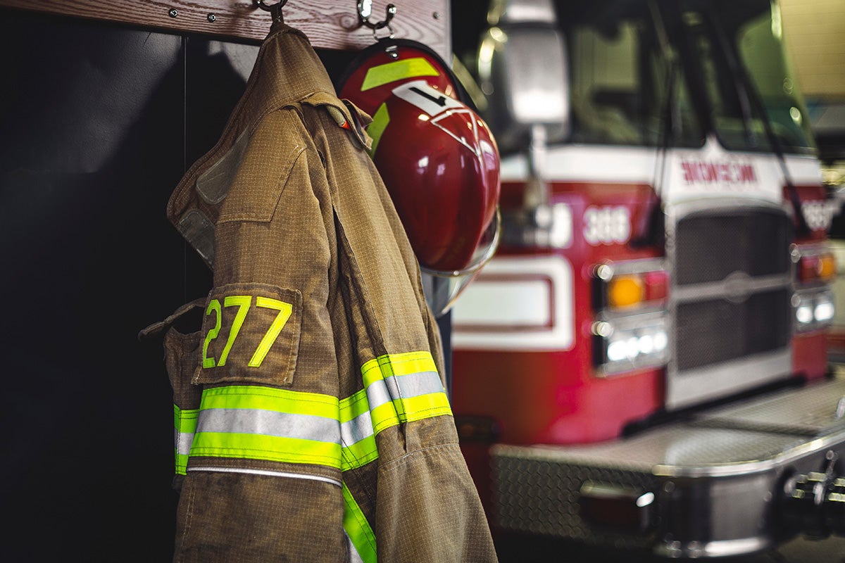 firefighter coats and gear hang on a rack