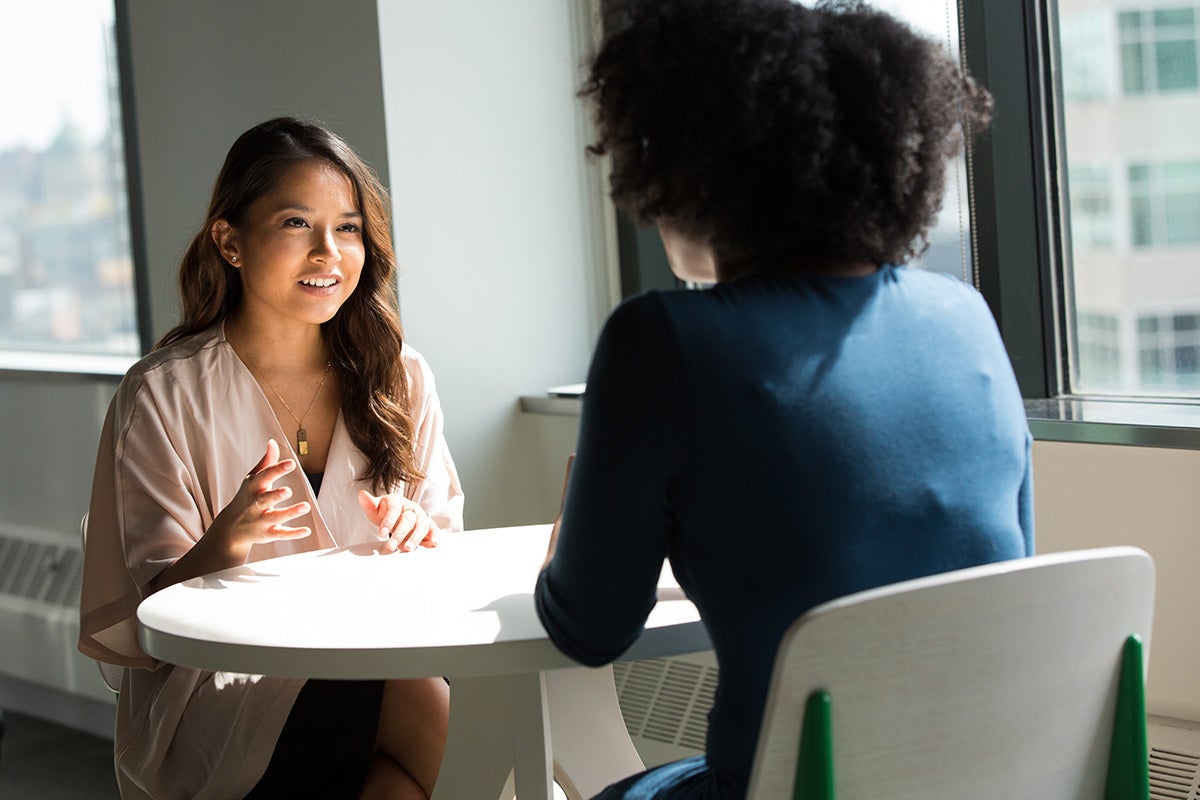 two women sitting at a table having a conversation