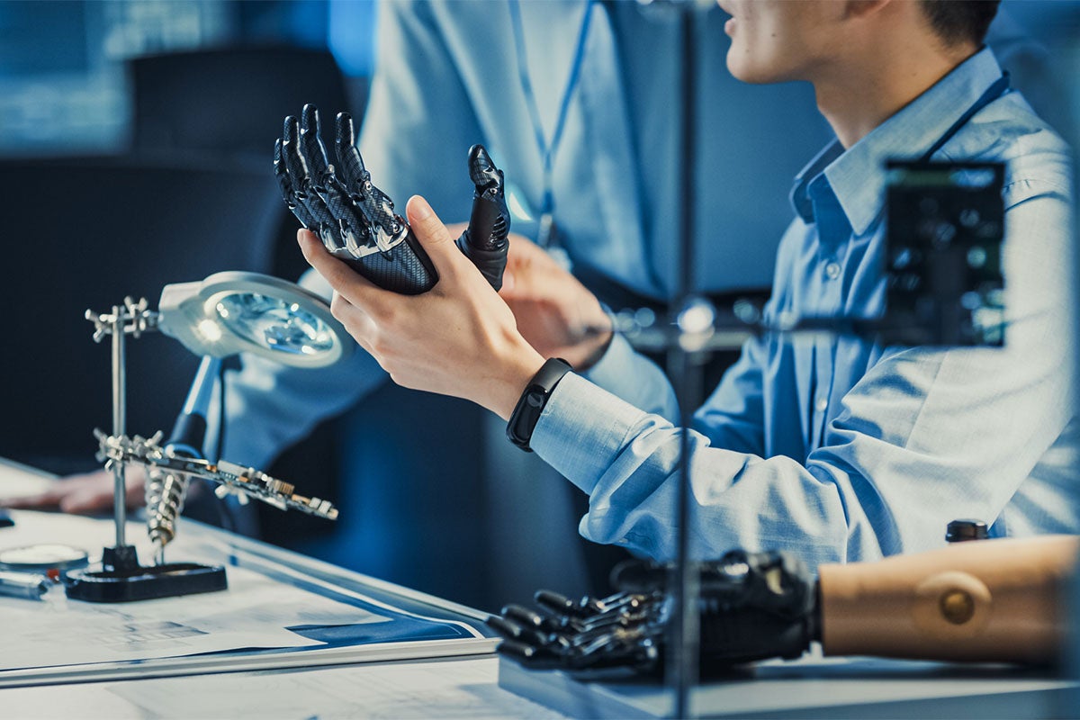 Cropped photo of man in a biomedical engineering lab holding a neurorobotic prosthetic hand in his hand.