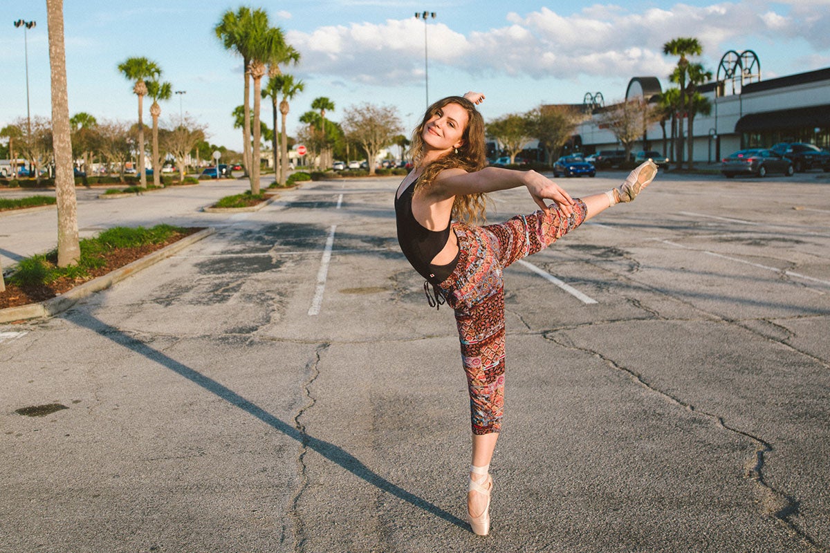 A ballet dancer poses for a photo in a parking lot