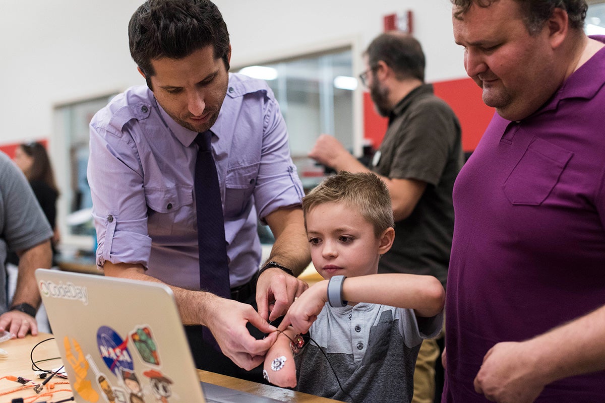 two men help a boy with his bionic limb