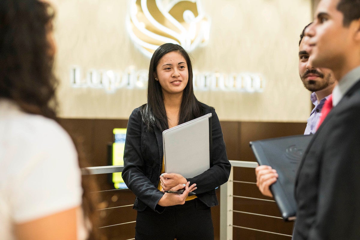 Students wearing business attire speaking in the UCF College of Business atrium