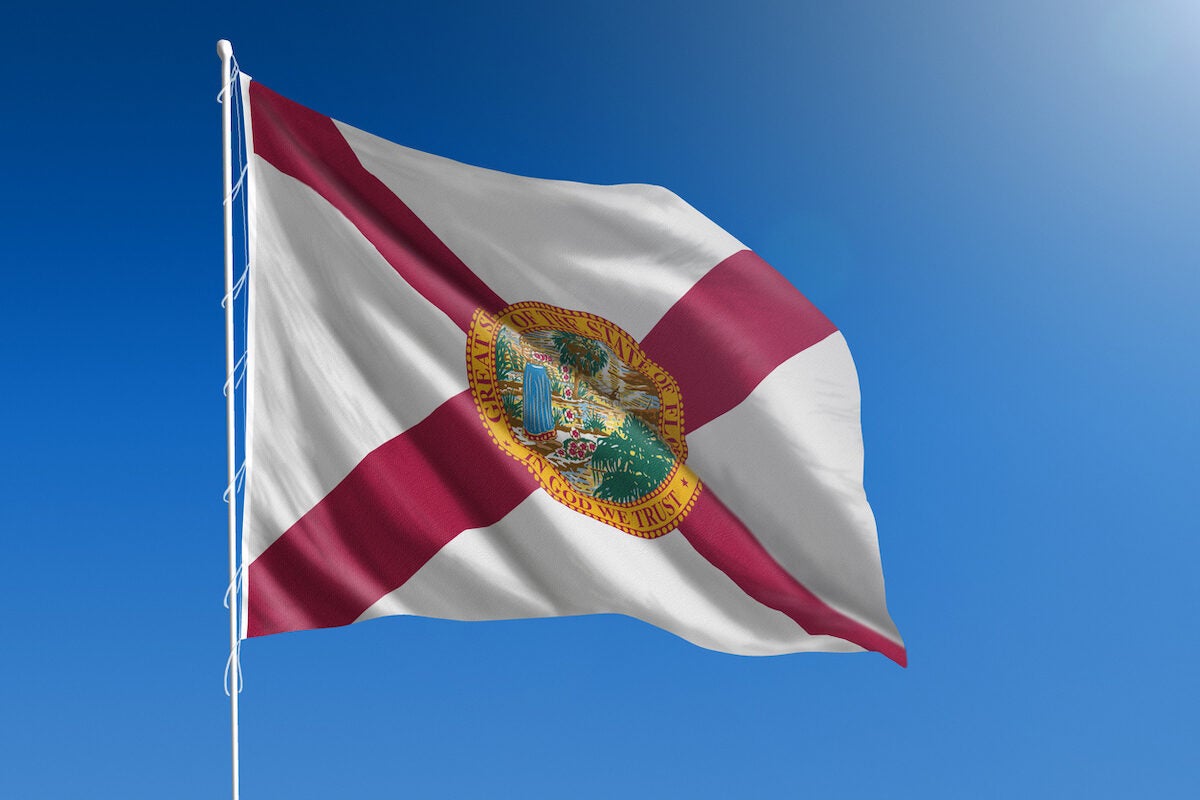 The flag of the state of Florida blowing in the wind in front of a clear blue sky