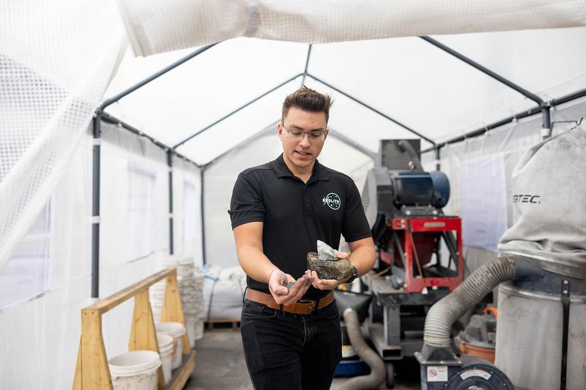 Konrad Krol holds a sample of simulate soil and rocks while inside the UCF Exolith Lab