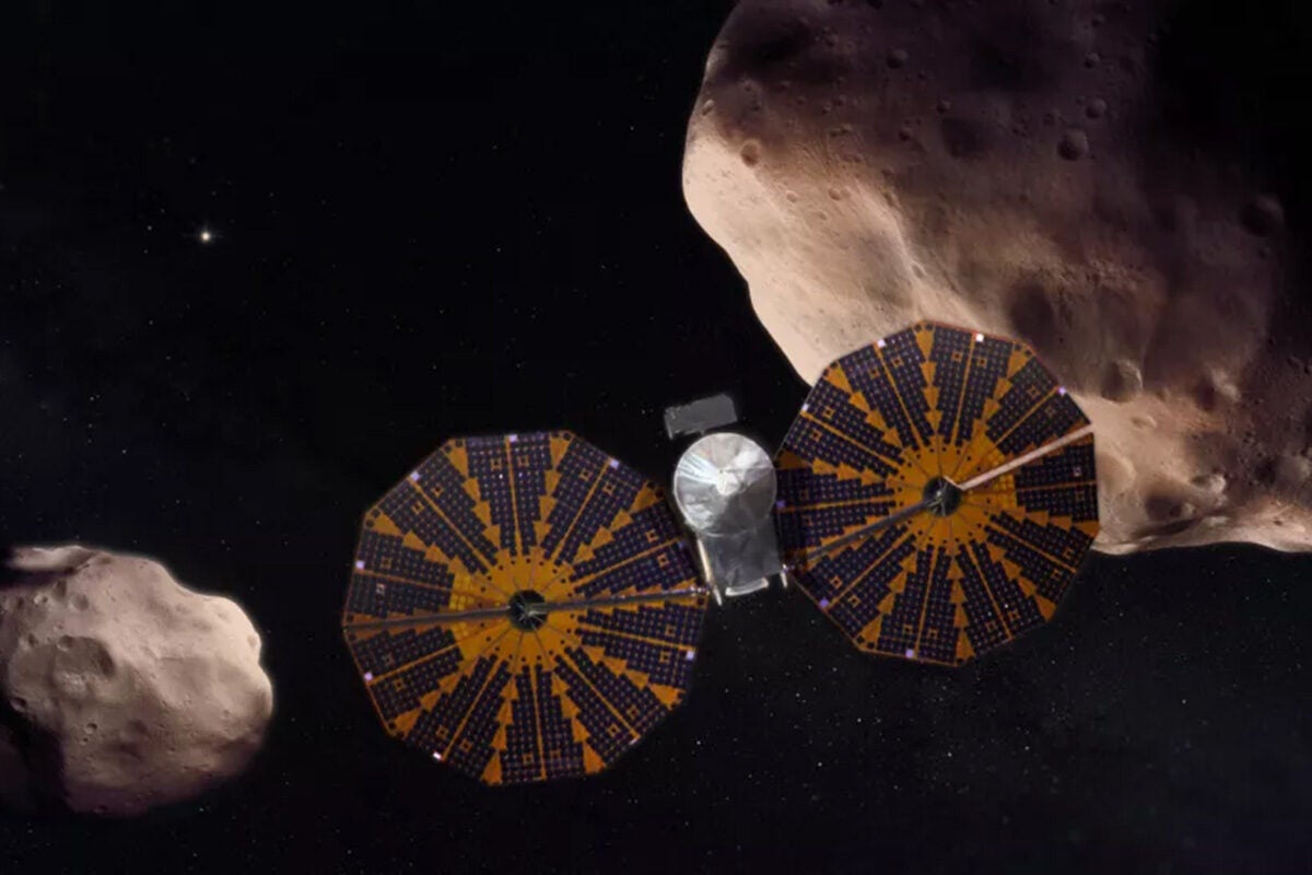 An artist's depiction of the Lucy spacecraft flying past two Trojan asteroids.