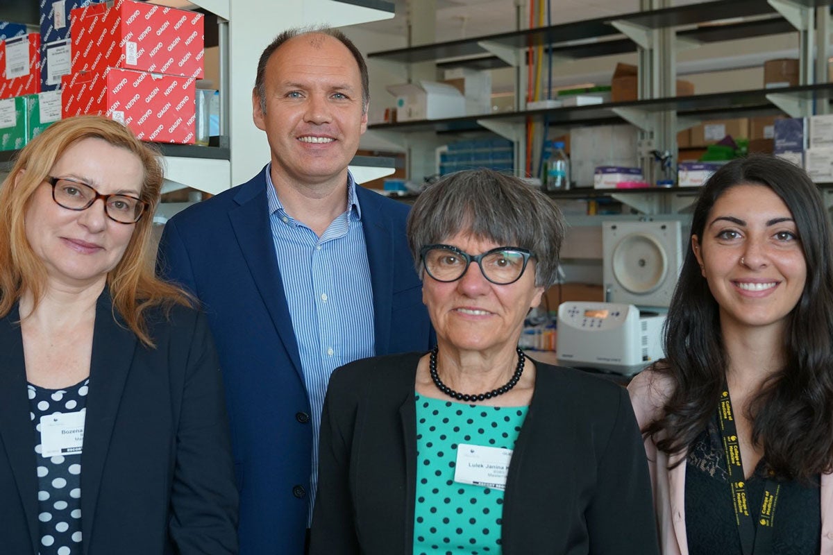 Three women and one man pose for a photo in a research lab