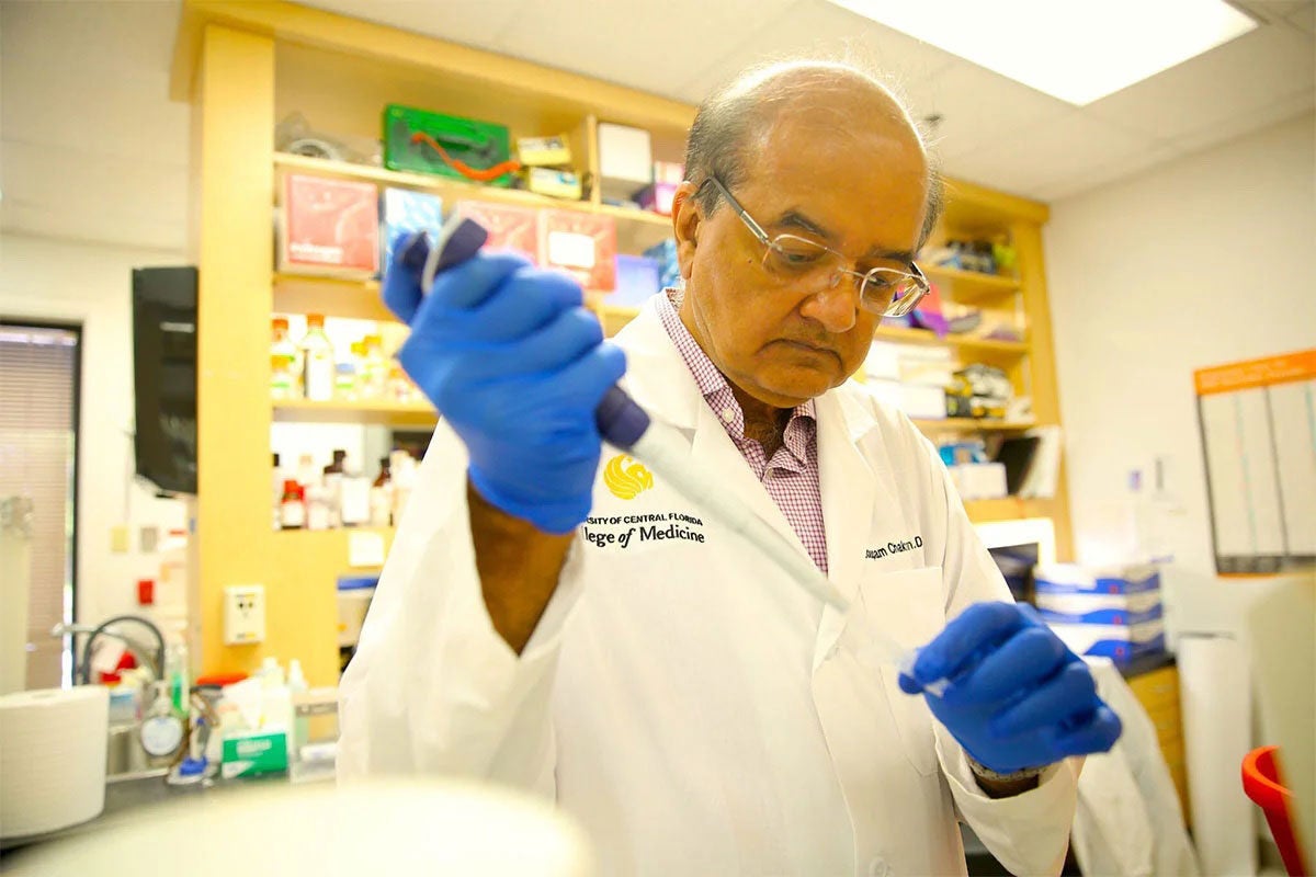 Debopam Chakrabarti wearing glows and using lab equipment