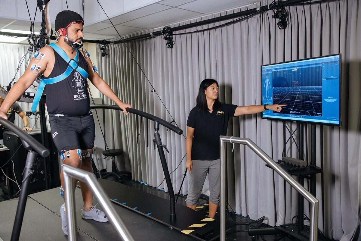 Helen Huang working with a participant, who is walking on a. treadmill, in her lab.